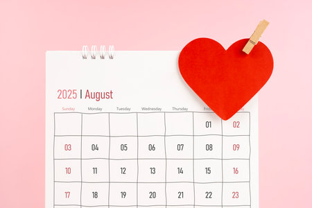 August 2025 desk calendar with red heart note on pink background.の写真素材
