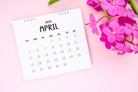 April 2026 desk calendar and pink orchid on pink background.の写真素材