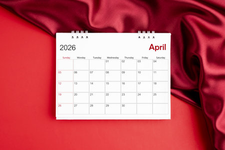 Top view of April 2026 desk calendar on red silk background.の写真素材