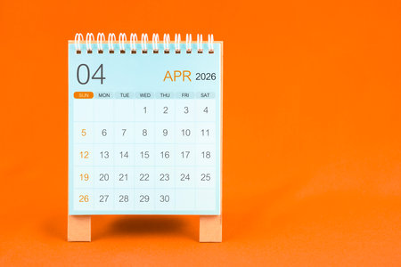 April 2026 desk calendar stand on orange textile background.の写真素材