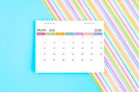 July 2026 desk calendar on blue and rainbow background.