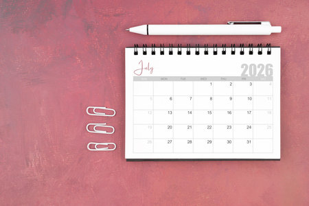 Desk calendar for July 2026 and pen with paper clips on red table.の写真素材