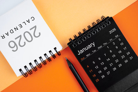 January 2026 desk calendar black and white color with pencil on orange background.