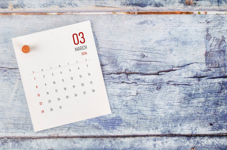 March 2026 monthly calendar and wooden push pin on wooden background.