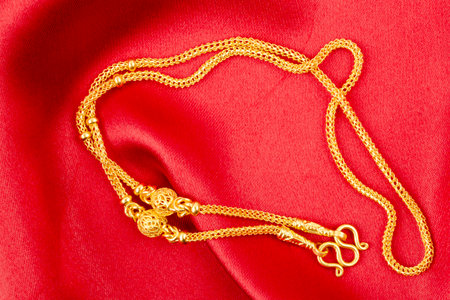 Gold chain necklace on red color silk textile.