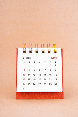 May 2026 white desk calendar on brown color background.