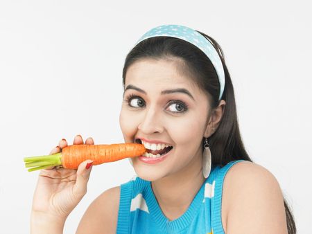 asian woman eating a carrotの写真素材