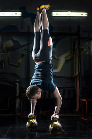 Man athlete standing upside down on kettlebellsの写真素材