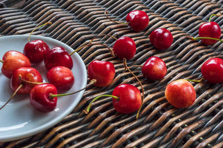 Cherries in the white dish and on the wicker backroundの写真素材
