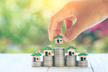 House placed on coins Men's hand is planning savings money of coins to buy a home concept concept...