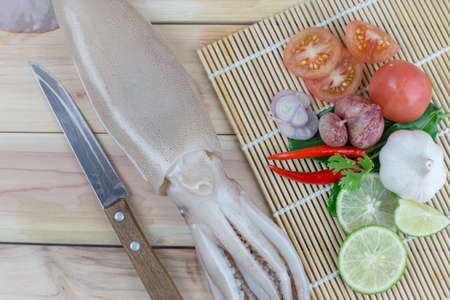fresh squid with lemon and parsley, chilli,tomato,garlic,Shallots. Whiteraw squid seafood or fresh squid display for sale at wet market for cooking in seafood or other menu on  wooden backgroundの写真素材