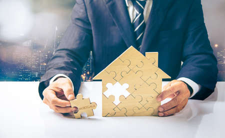 Mortgage concept. Financial agent complete wooden model of the house with last piece with text mortgage. concept real estate investment.  for saving or investment for a house,の写真素材