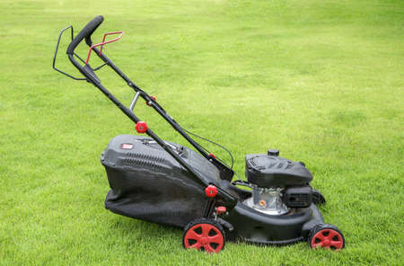 Lawn mower on green grass. mowing gardener care work tool close up view sunny dayの写真素材