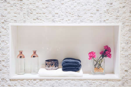 White and blue towels are neatly folded placed in the bathroom on a shelf in light interior and beautiful white brick wall mantelpieceの写真素材