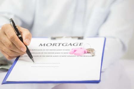 Mortgage concept. Just put your signature here! Confident young man in shirt and tie holding some...