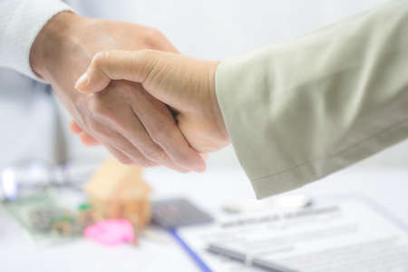 Real estate broker and customer shaking hands after signing a contract: real estate, home loan and...