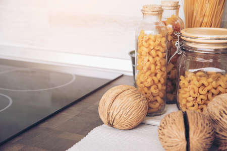 pasta in the jar. on kitchen shelves are different kinds of pasta in glass jars and Gas stove in modern kitchenの写真素材