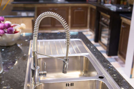 Designed kitchen with glossy countertop and stainless steel faucet