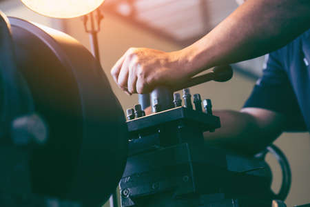Professional machinist : man operating lathe grinding machine - metalworking industry concept....