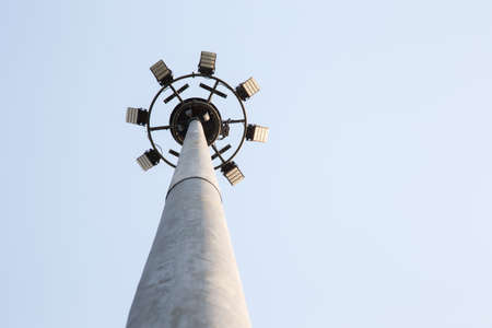 Spotlights tower with a metal pole for the sports arena. Installed around football stadium. Blue sky background.の写真素材