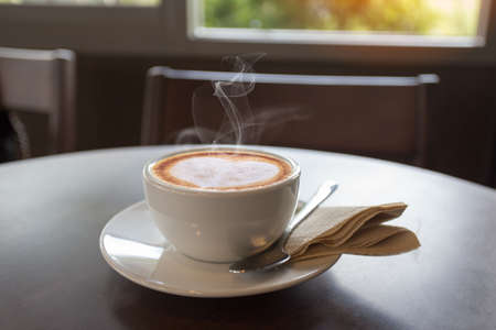 Coffee in White cup on wooden table in cafe with lighting background. coffee latteの写真素材