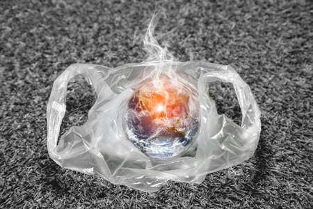 The concept of World Environment Day.  the earth in a plastic bag. Dead grassland background. Global warmingの写真素材