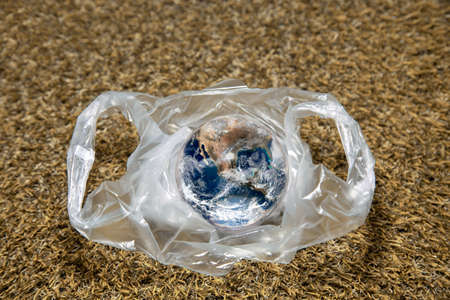 The concept of World Environment Day.  the earth in a plastic bag. Dead grassland background. Global warmingの写真素材