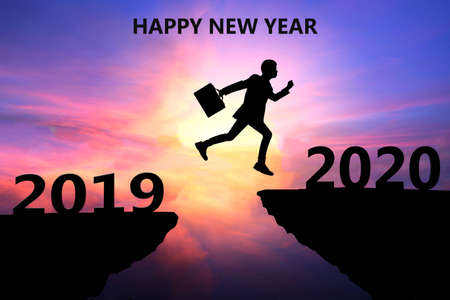 Happy New Year 2020 Silhouette. Young man jumps over a cliff in 2019 to a cliff in 2020. Sunset time