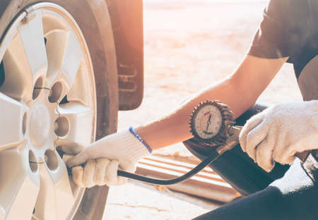 Asian man car inspection Measure quantity Inflated Rubber tires car.Close up hand holding machine Inflated pressure gauge for car tyre pressure measurement for automotive, automobile imageの写真素材