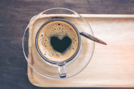 Cup of coffee with heart shape on Wooden background. Top view with copy space.の写真素材