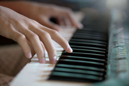 Playing the piano keyboard close up ,Cropped hands of kid playing piano in the classroom. An image...