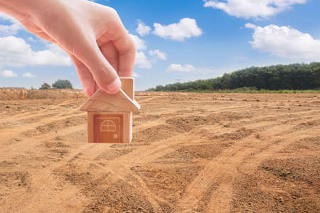 House symbol with location pin and Empty dry cracked swamp reclamation soil, land plot for housing construction project with and beautiful blue sky with fresh air Land for sales landscape conceptの写真素材
