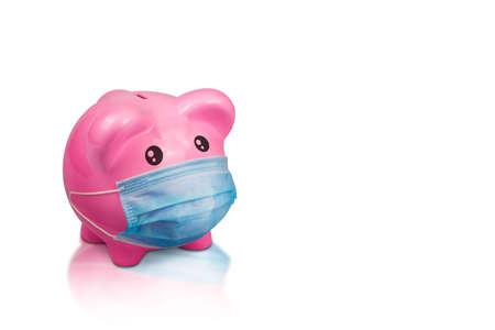 Pink ceramic piggy bank wearing surgical mask on isolate background with copy space. Concept for money saving plan, healthcare insurance, coronavirus economic crisis, or financial accountingの写真素材
