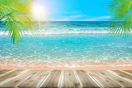 Empty brown wooden table. beautiful nature green palm leaf on tropical beach with bokeh background of abstract  ,can be used for montage or display your productsの写真素材