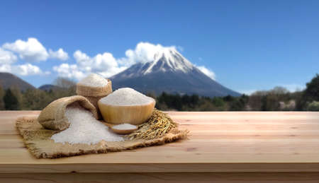 Asian uncooked white rice and burlap sack on wooden table Mount Fuji Background. rice grains healthy food, for design, advertisingの写真素材