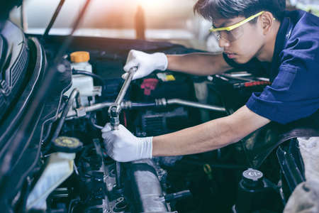 Auto mechanic working on car engine in mechanics garage. Repair service. Automotive Car repair...
