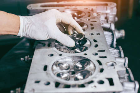 Auto mechanic working in garage. Repair service.  opened automobile engine cylinder head for maintenance repair at car service station for diagnosisの写真素材