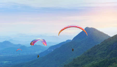 Paragliding in the sky. Paraglider  flying over Landscape sun set Concept of extreme sport, taking adventure challenge.の写真素材