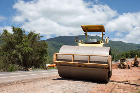 Roller rolling fresh hot asphalt on the new road. Road construction. The road rollers working on the...