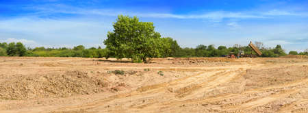 A truck is moving into sand at a ground leveling construction site., land plot for housing construction project with car tire print in rural area Land for sales landscape concept.の写真素材