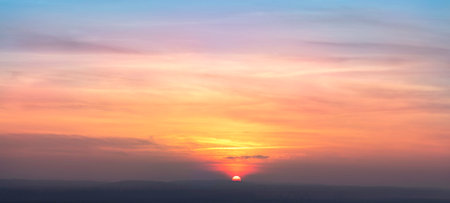 Real amazing panoramic sunrise or sunset sky with gentle colorful clouds. Long panorama, crop it. Evening sky scene with golden light from the setting sunの写真素材