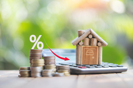 Houses and coins laying on a wooden table as a ladder with a white illustration showing a decrease in interest rates. plan savings money of coins to buy house ideas for property ladder, mortgage.の写真素材