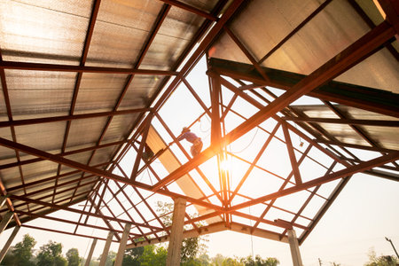 Roof repair, Construction worker installing new roof, roofing tools, power drill used on new roof with sheet metal. Roofing - construction worker standing on a roof covering it with metal.の写真素材