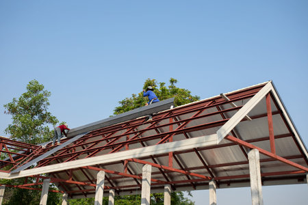 Roof repair, Construction worker installing new roof, roofing tools, power drill used on new roof with sheet metal. Roofing - construction worker standing on a roof covering it with metal.の写真素材