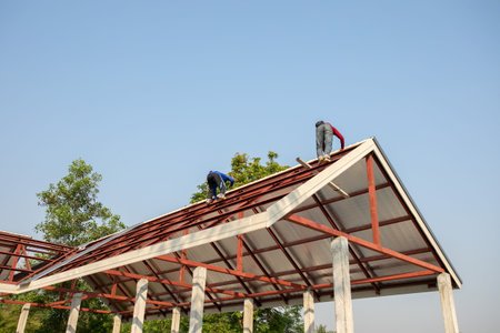 Roof repair, Construction worker installing new roof, roofing tools, power drill used on new roof with sheet metal. Roofing - construction worker standing on a roof covering it with metal.の写真素材