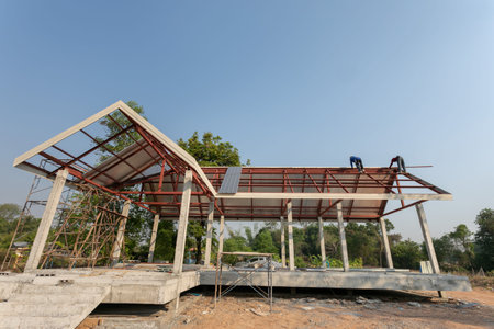 Roof repair, Construction worker installing new roof, roofing tools, power drill used on new roof with sheet metal. Roofing - construction worker standing on a roof covering it with metal.の写真素材