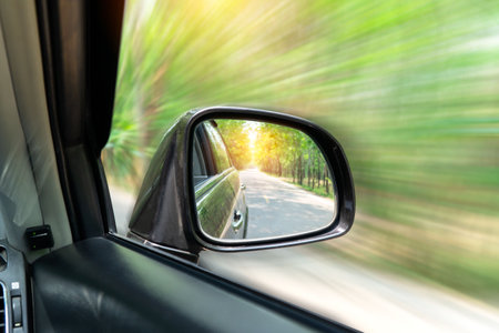 look in the rear view mirror of a carLandscape in the sideview mirror of a car , on road countryside.の写真素材