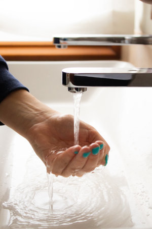 Girl washing her hand, collecting water from the bathroom tapの写真素材