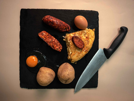 Indulge in the Spanish culinary heritage with this mouthwatering potato omelette served on a sleek black slate tray. Each slice reveals a delightful blend of tender potatoes, farm-fresh eggs, and savory chorizo, creating a symphony of flavors that captivate the senses.の写真素材