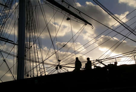 A view of tourists visiting the Cutty Sark in Greenwich, London at sunset.